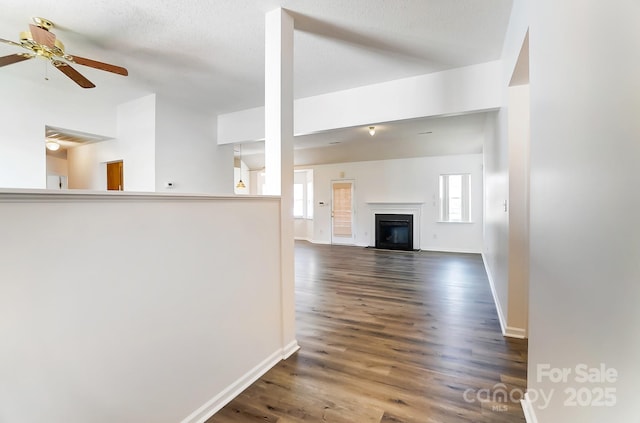 unfurnished living room featuring baseboards, wood finished floors, ceiling fan, and a healthy amount of sunlight