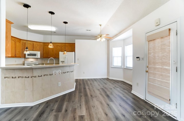 kitchen with dark wood-style flooring, a ceiling fan, white appliances, light countertops, and hanging light fixtures