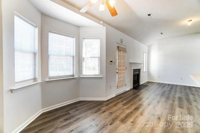 unfurnished living room with visible vents, a glass covered fireplace, a ceiling fan, and wood finished floors