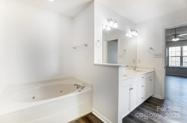 full bathroom featuring baseboards, wood finished floors, a sink, and a whirlpool tub