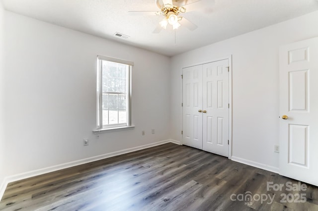 unfurnished bedroom with dark wood-style floors, baseboards, multiple windows, and visible vents