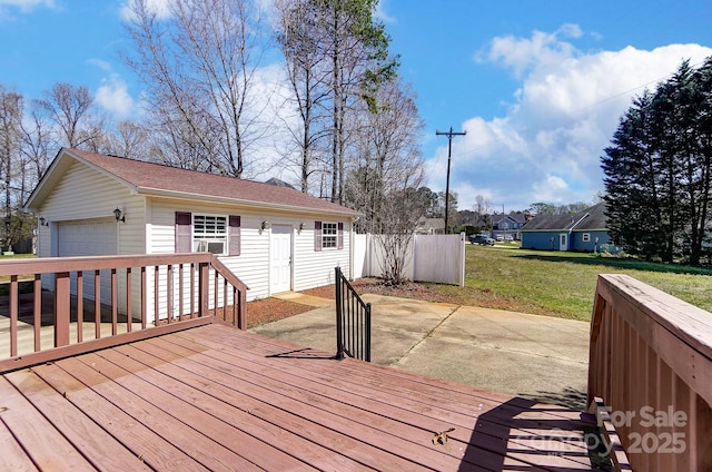 wooden terrace featuring fence, cooling unit, an outbuilding, a detached garage, and a lawn