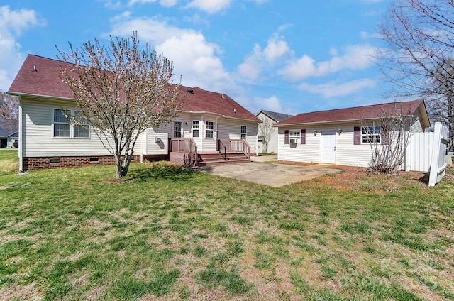 rear view of house featuring a shingled roof, a yard, crawl space, a wooden deck, and a patio