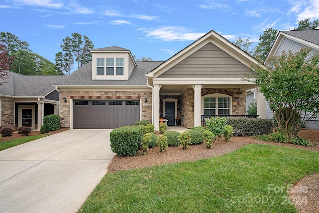 view of front of property with a front lawn, covered porch, and a garage