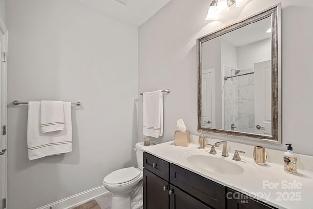 bathroom featuring vanity, tiled shower, and toilet