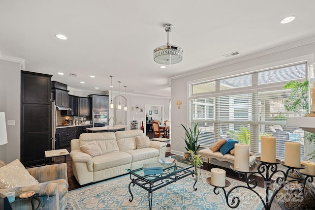 living room with sink, ornamental molding, and light hardwood / wood-style floors