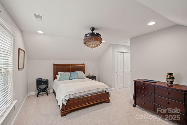 bedroom with lofted ceiling, light carpet, and a closet