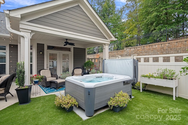 wooden deck featuring a hot tub, a patio, ceiling fan, and a lawn