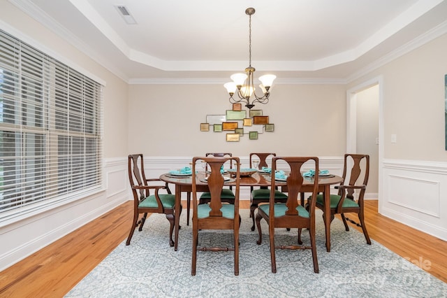 dining room with crown molding, a tray ceiling, an inviting chandelier, and hardwood / wood-style flooring