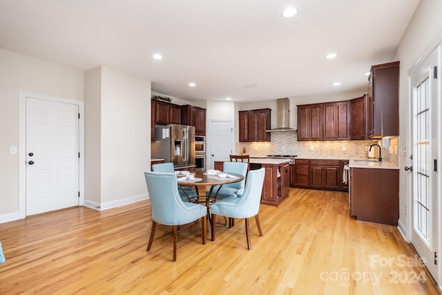 kitchen featuring light wood-type flooring, a wealth of natural light, sink, wall chimney range hood, and appliances with stainless steel finishes