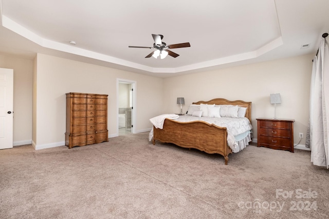 bedroom featuring a raised ceiling, light carpet, and ceiling fan