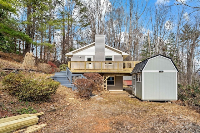 rear view of property with a shed and a deck