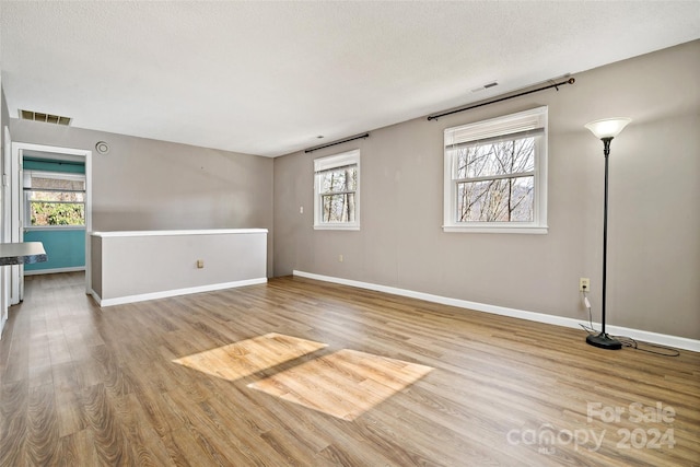 unfurnished room featuring a textured ceiling, light wood-type flooring, and plenty of natural light