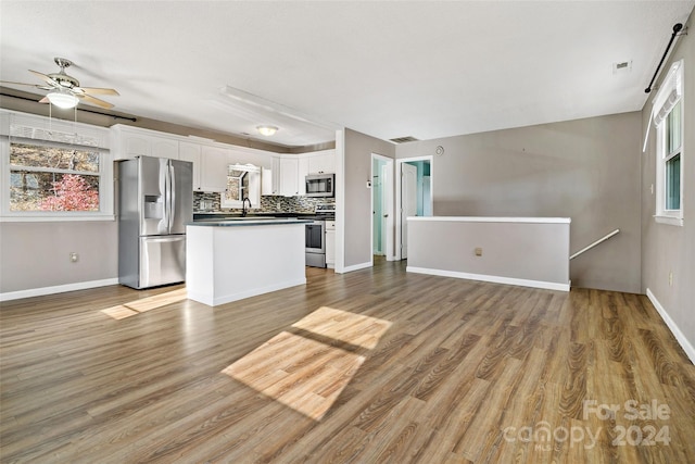 kitchen with white cabinets, decorative backsplash, ceiling fan, light wood-type flooring, and appliances with stainless steel finishes