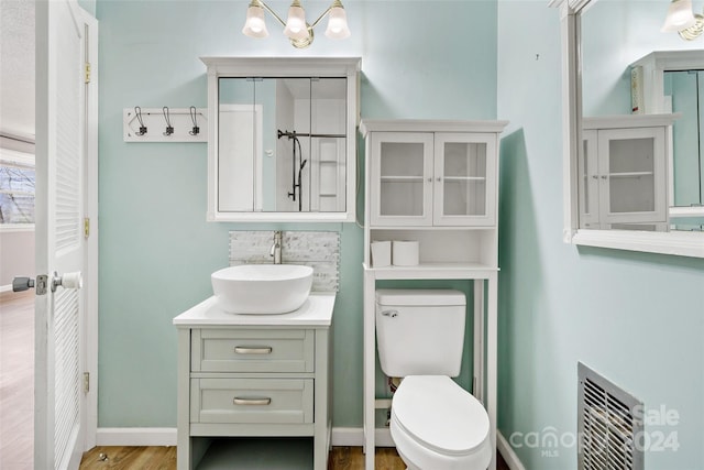 bathroom with wood-type flooring, vanity, heating unit, and toilet