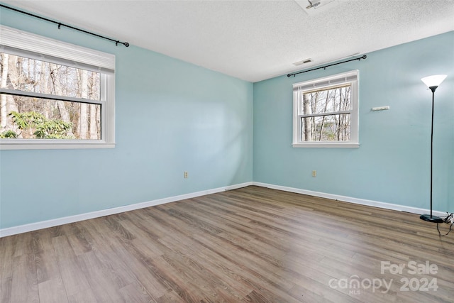 spare room featuring hardwood / wood-style floors and a textured ceiling