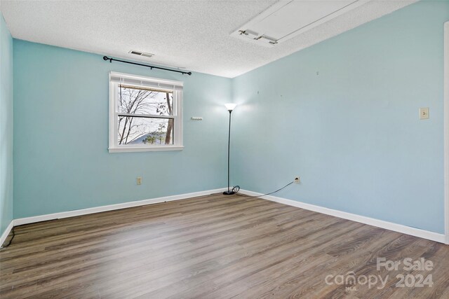 spare room featuring hardwood / wood-style flooring and a textured ceiling