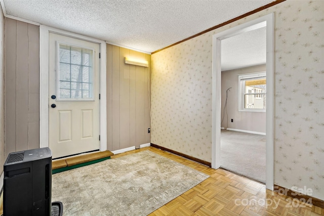 foyer entrance with a textured ceiling, wooden walls, and light parquet flooring