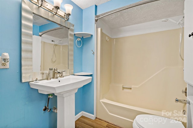 bathroom with wood-type flooring, a textured ceiling, shower / bath combination, and toilet