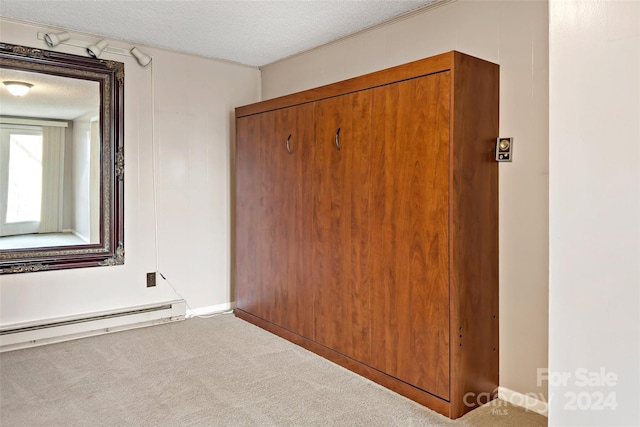 unfurnished bedroom with baseboard heating, carpet flooring, and a textured ceiling