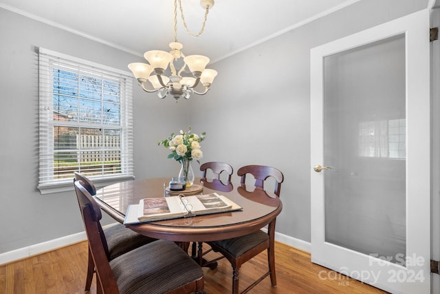 dining room featuring hardwood / wood-style floors, ornamental molding, and a notable chandelier