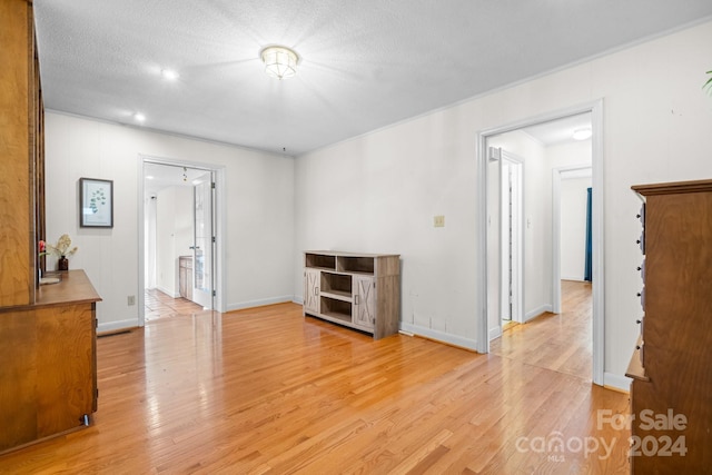 empty room with a textured ceiling and light hardwood / wood-style flooring