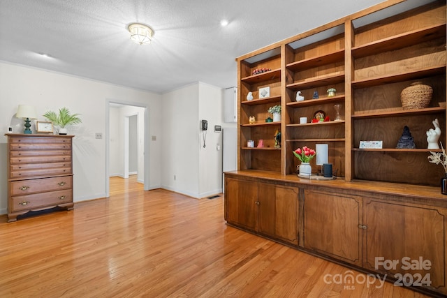 unfurnished office featuring light wood-type flooring and a textured ceiling