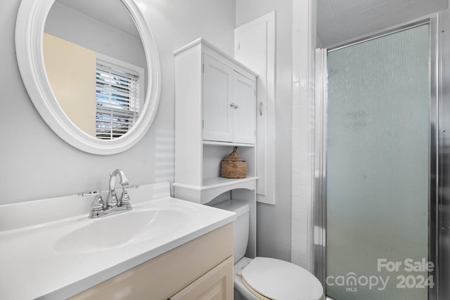 bathroom featuring vanity, an enclosed shower, and toilet