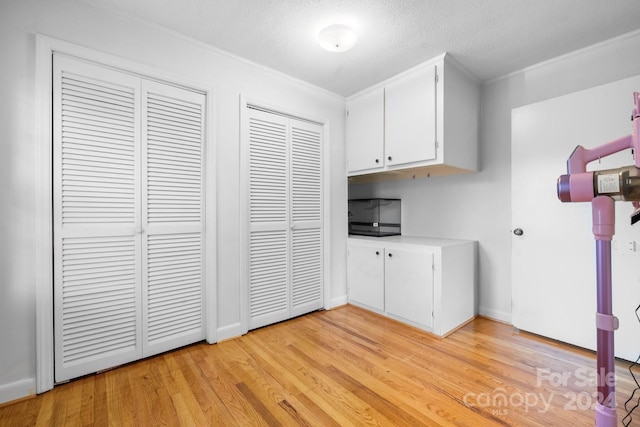 laundry room featuring ornamental molding, a textured ceiling, and light wood-type flooring