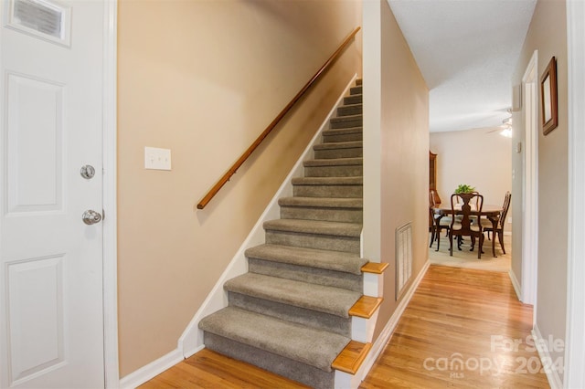 stairs featuring wood-type flooring and ceiling fan