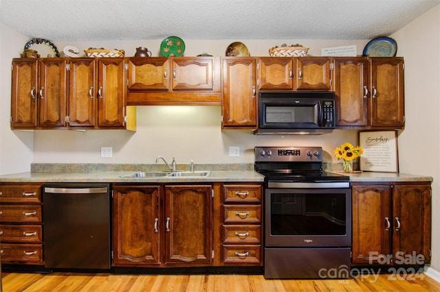 kitchen featuring a textured ceiling, stainless steel appliances, light wood-type flooring, and sink