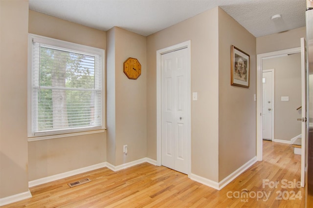 hall featuring a textured ceiling and light hardwood / wood-style flooring