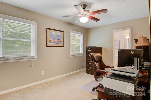 carpeted home office with a textured ceiling, a healthy amount of sunlight, and ceiling fan