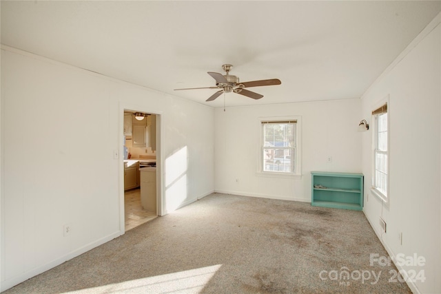 carpeted spare room featuring ceiling fan and crown molding