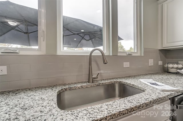 details with light stone countertops, sink, decorative backsplash, and white cabinetry