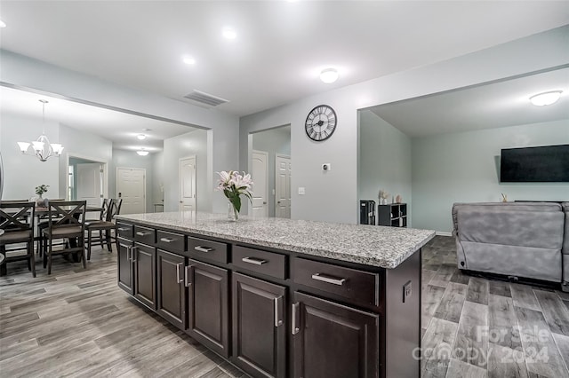 kitchen featuring pendant lighting, a chandelier, a center island, light hardwood / wood-style flooring, and dark brown cabinetry