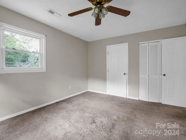 unfurnished bedroom with carpet, a textured ceiling, and ceiling fan