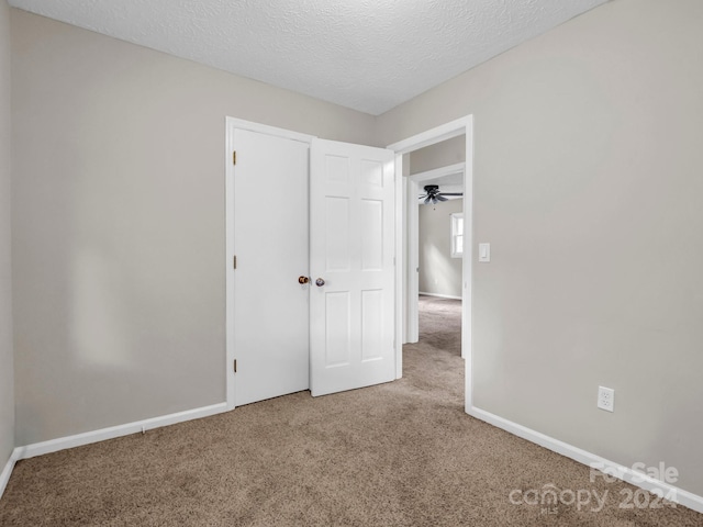 unfurnished bedroom with a closet, carpet, and a textured ceiling