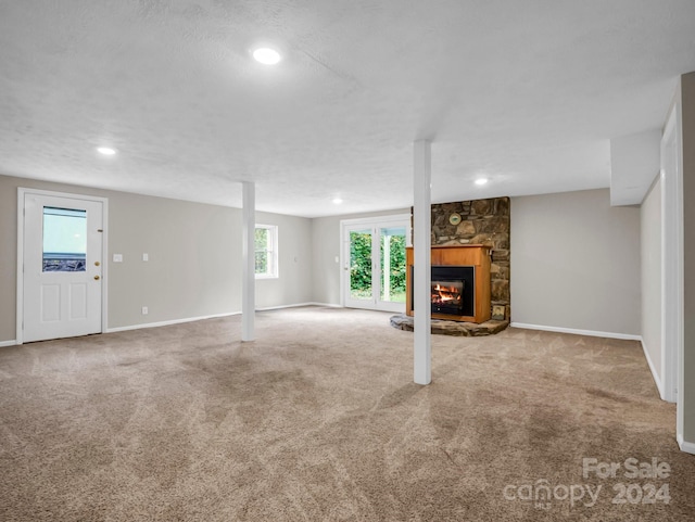 unfurnished living room featuring a textured ceiling, a fireplace, and carpet floors