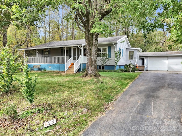 view of front of home featuring a garage, a front lawn, an outbuilding, and a porch