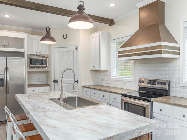 kitchen with sink, white cabinetry, decorative light fixtures, appliances with stainless steel finishes, and custom range hood