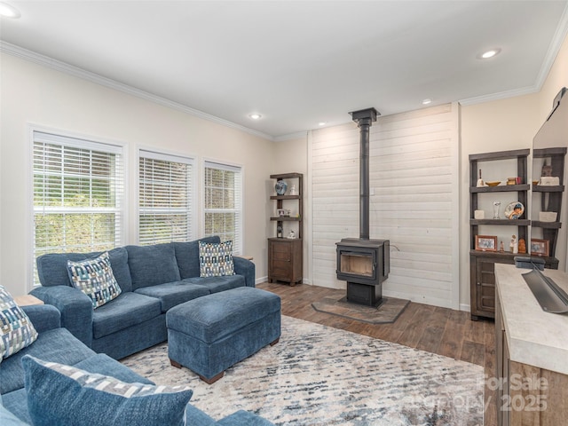 living room featuring plenty of natural light, ornamental molding, wood-type flooring, and a wood stove