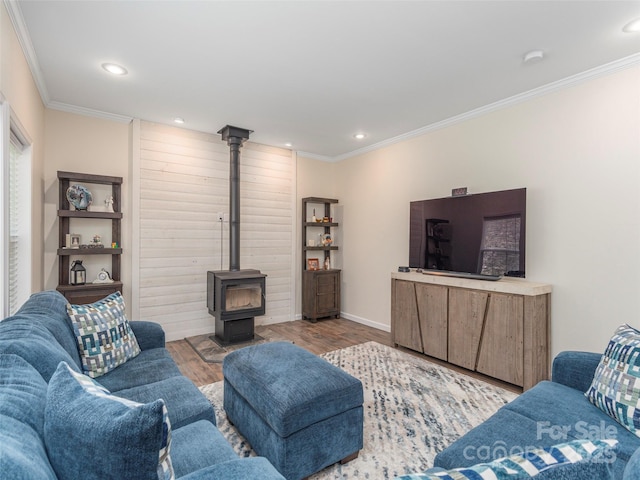 living room with crown molding, a wood stove, and light wood-type flooring