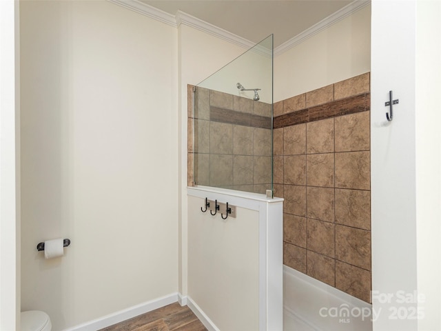 bathroom featuring tiled shower, ornamental molding, toilet, and wood-type flooring