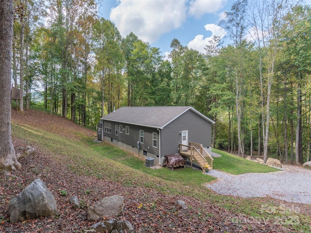 view of property exterior with cooling unit and a lawn