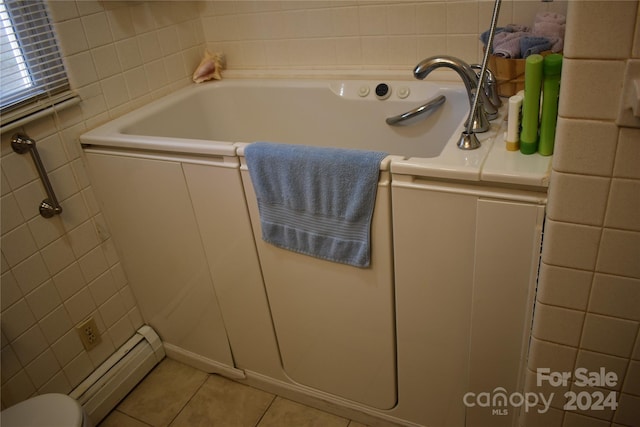 bathroom with a tub, a baseboard heating unit, and tile patterned flooring