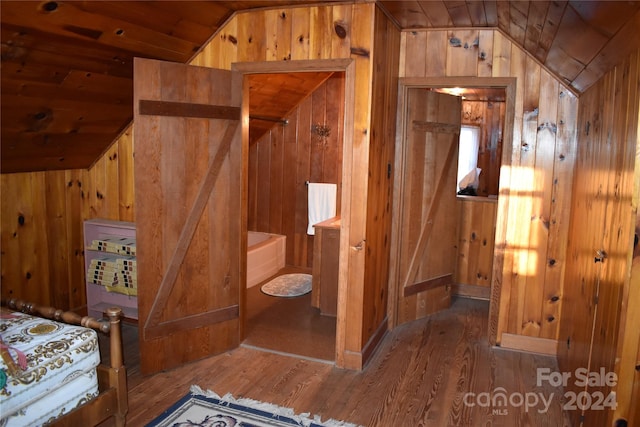 bathroom featuring lofted ceiling, hardwood / wood-style floors, and wooden walls