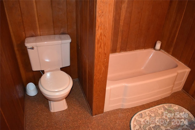 bathroom with a bathtub, toilet, and wooden walls