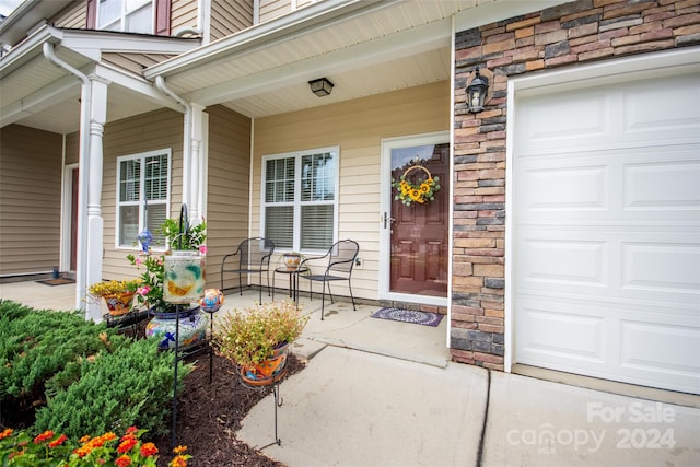 property entrance featuring covered porch and a garage