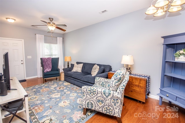 living room featuring ceiling fan with notable chandelier and dark hardwood / wood-style floors